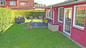 A red house with a backyard patio area featuring outdoor furniture and a hot tub.