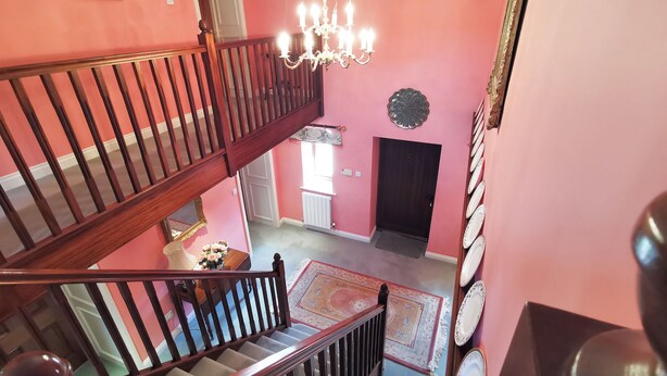 Um interior com vários níveis, escada, lustre e porta.