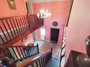 Un int érieur à plusieurs niveaux, avec un escalier, un lustre et une porte.