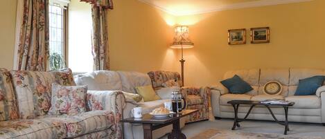 A living room with floral-patterned sofas, a coffee table, a lamp, and a rug.