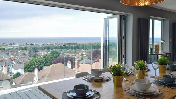 A dining area with a view of the sea and cityscape. - 3 bedroom accommodation in Prestatyn (Prestatyn)