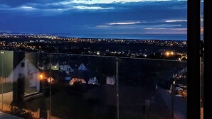 A nighttime view from a balcony overlooking a cityscape with distant lights and a cloudy sky. - 3 bedroom accommodation in Prestatyn (Prestatyn)
