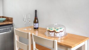 A dining table with a bottle of wine, two glasses, and a glass cake on a wooden table. - Bullions Farm Cottage (Consett)