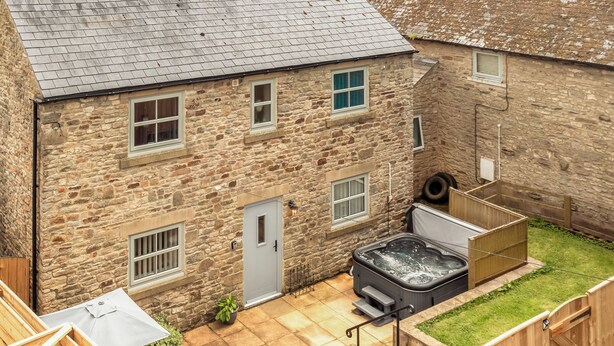 A stone building with a hot tub, a door, and a window. - Bullions Farm Cottage (Consett)