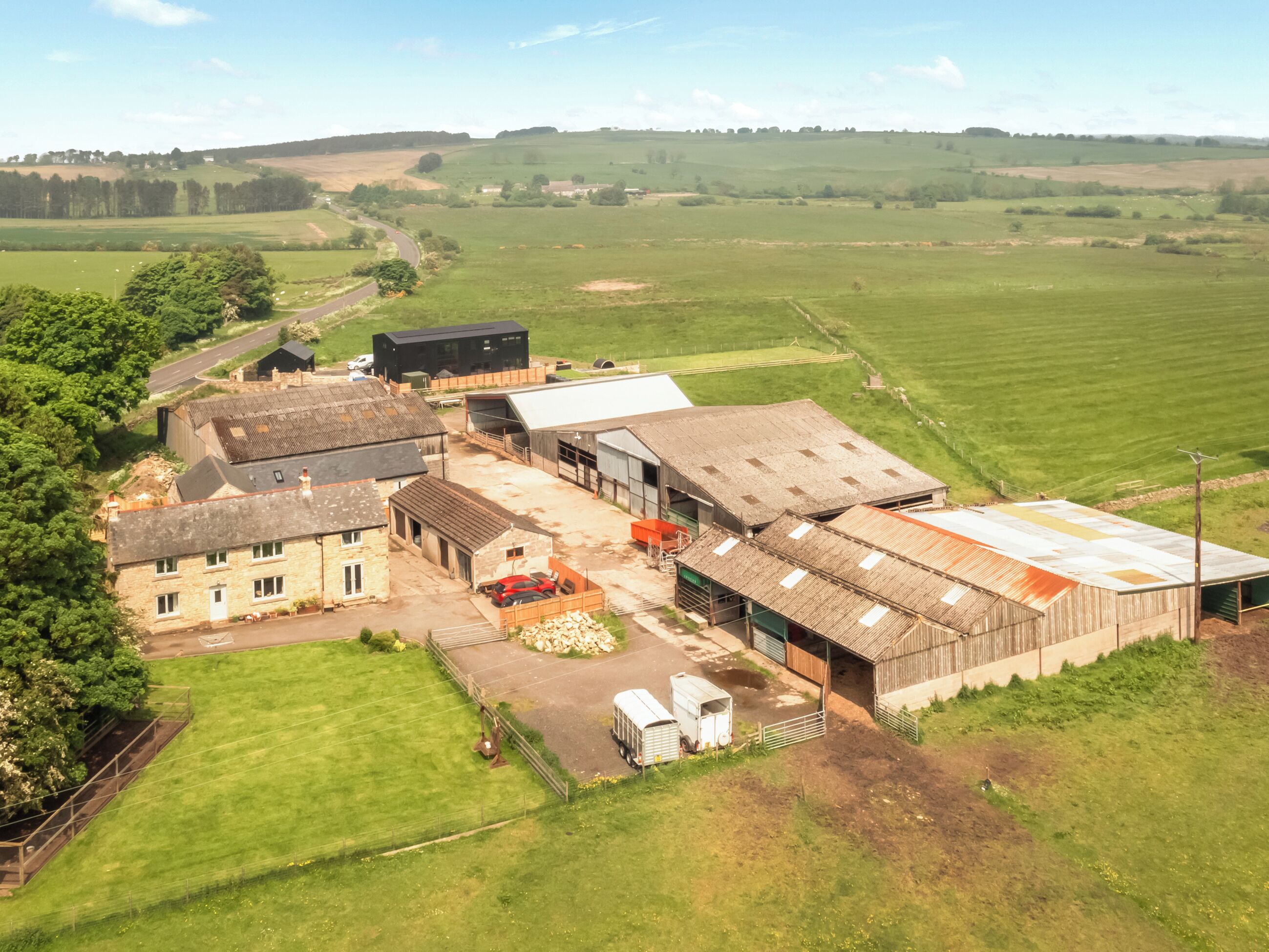 An aerial view of a rural farm with barns, a silo, and a small road.