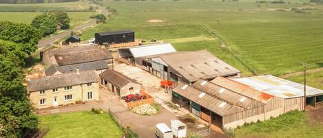 An aerial view of a rural farm with barns, a silo, and a small road.