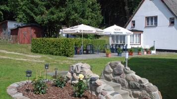 Ein Hotel mit Außenbereich, einem Garten mit Rosenbusch und einer Steinmauer.