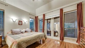 A bedroom with a bed, wooden flooring, a dresser, and a sliding glass door leading to a balcony. - PRIVATE, SECLUDED LAKEFRONT RETREAT WITH BOAT DOCK, LARGE PATIOS AND HOT TUB!! (Runaway Bay)