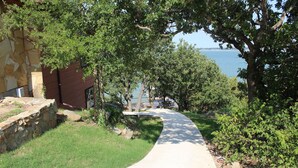 A curved pathway leading to a body of water, surrounded by greenery and a stone wall. - PRIVATE, SECLUDED LAKEFRONT RETREAT WITH BOAT DOCK, LARGE PATIOS AND HOT TUB!! (Runaway Bay)