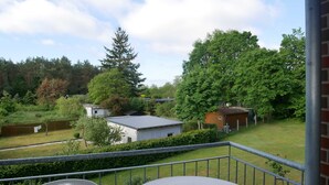 Een balkon met uitzicht op een gazon, een houten hek en een metalen balustrade.