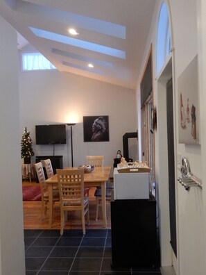 A dining area with a wooden table and chairs, a Christmas tree, and a flat-screen TV mounted on the wall.