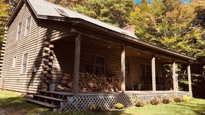 Una baita di legno con un portico, scale in legno e una recinzione a graticcio.