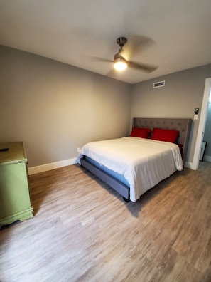 Un dormitorio con una cama, un ventilador de techo y un aparador verde.