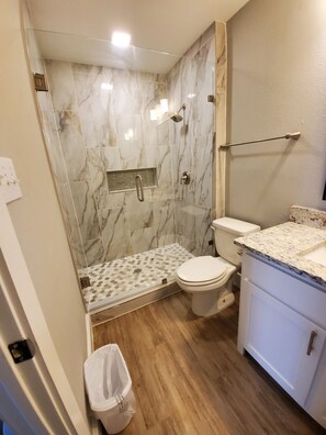 Une salle de bain avec douche, toilettes et lavabo.