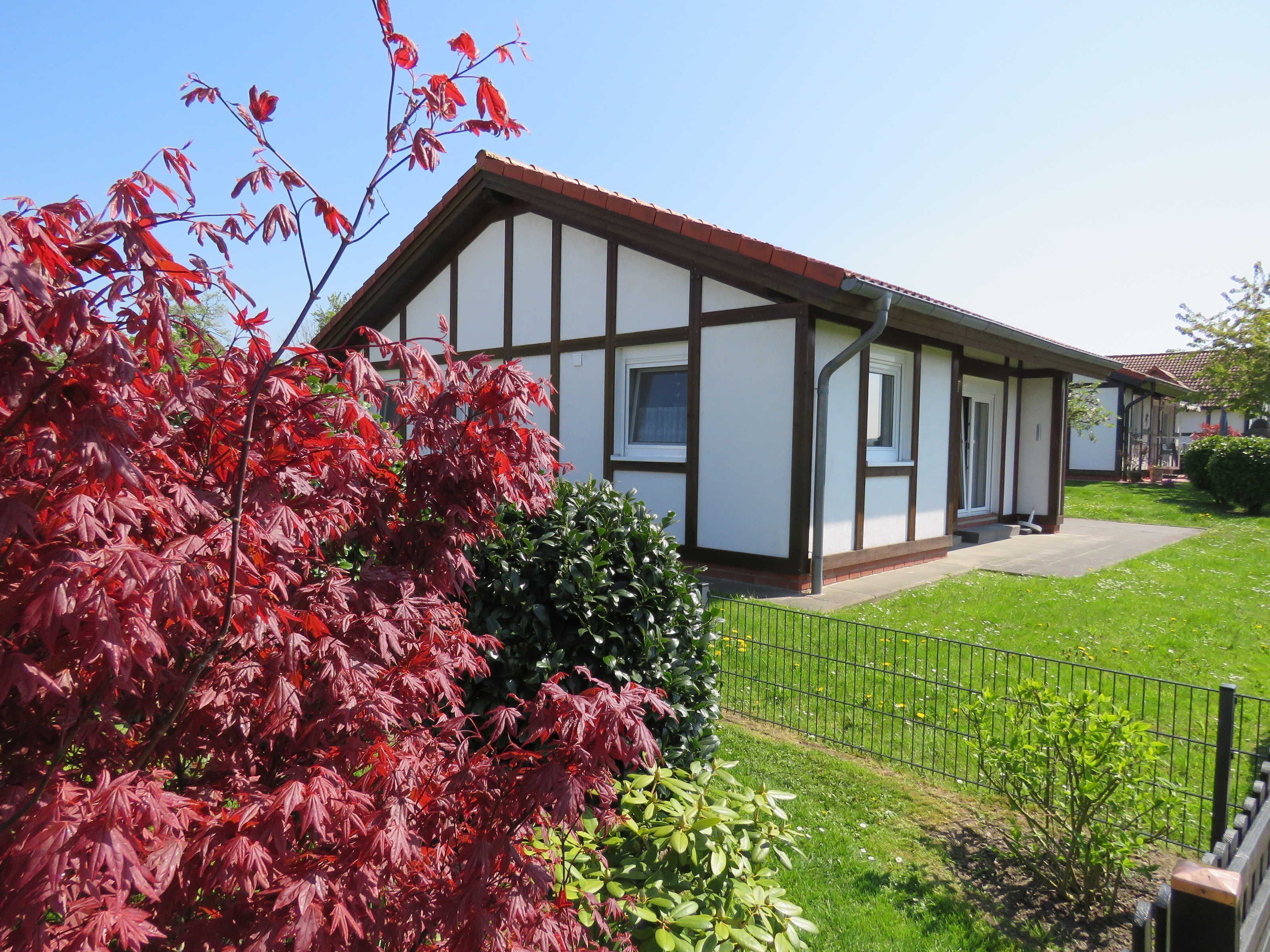 A traditional half-timbered house with a well-maintained lawn and a metal fence.