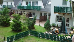 Un bâtiment à deux étages doté d’un balcon, d’un espace extérieur aménagé pour s’asseoir et d’un jardin clôturé.