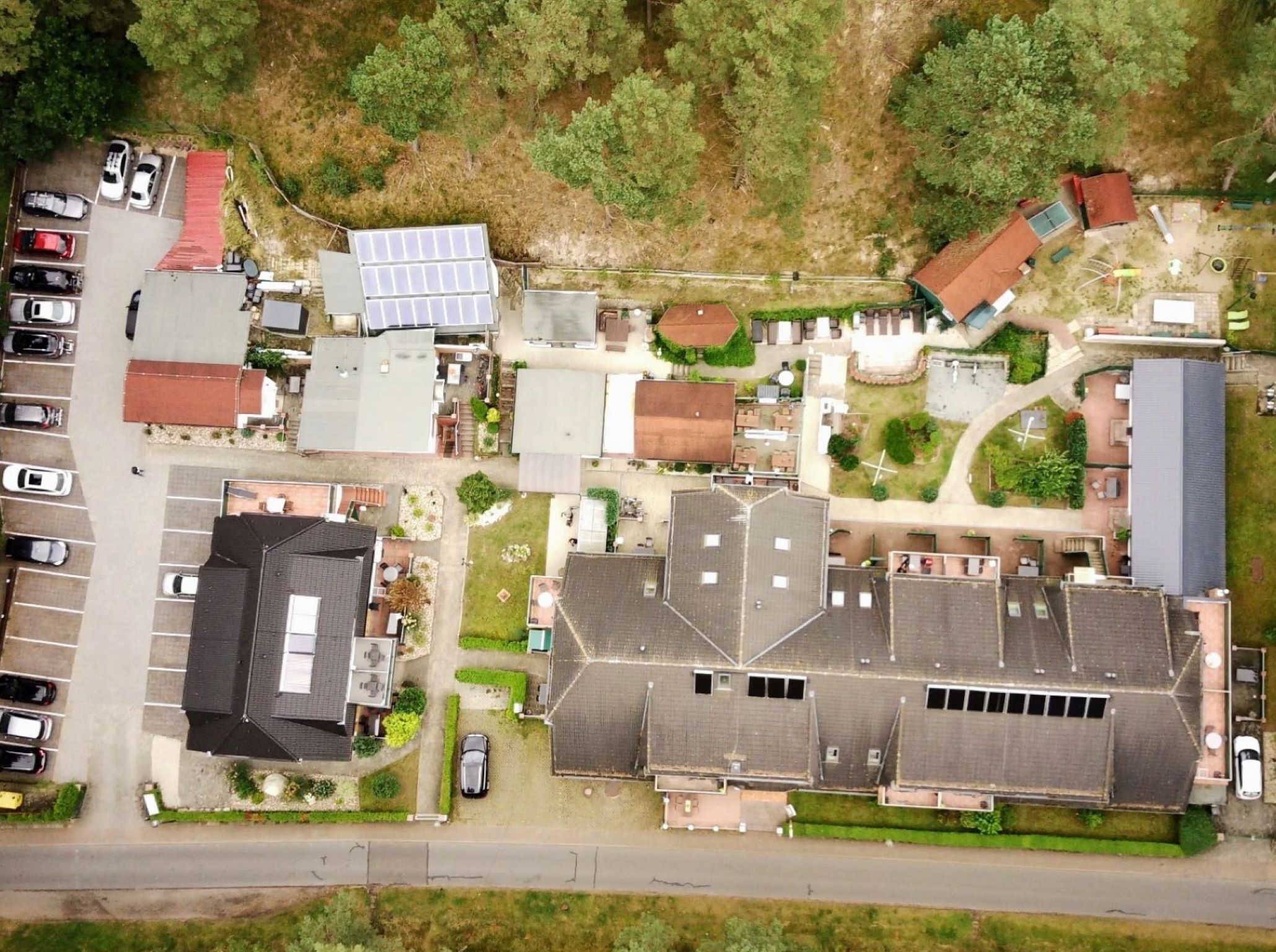 An aerial view of a residential area with multiple houses, a parking lot, and a small green space.