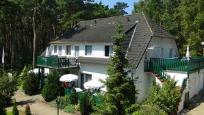 Un bâtiment à deux étages doté d’un balcon et d’un espace extérieur aménagé pour s’asseoir.