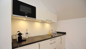 Een moderne keuken met een magnetron, spoelbak en aanrecht.