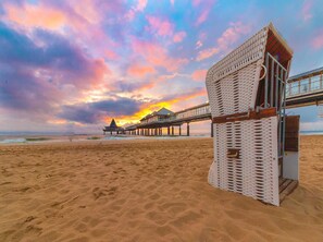 A beach with a wooden pier leading to a building with a triangular roof. - Double room - Hotel Am Gothensee (Heringsdorf)