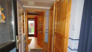 A narrow hallway with wooden doors and a tiled floor.