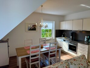 A kitchen with white cabinets, a black countertop, a stove, and a window with a view of greenery.