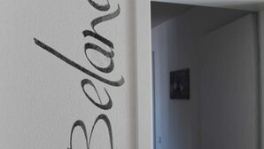 A hallway with a white wall featuring the name "Belana" in a decorative script.