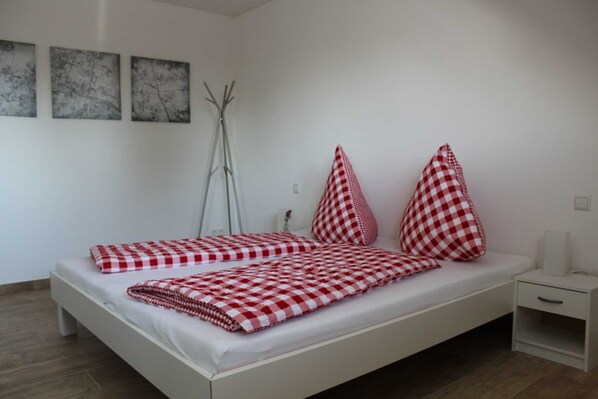 Une chambre à coucher moderne avec un lit blanc, une literie à carreaux et une table de chevet.