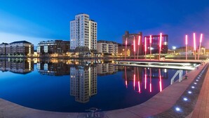 A nighttime cityscape with a calm water body reflecting buildings. - Grand Canal Dock Waterfront Luxury “Special Offer” (Dublin)