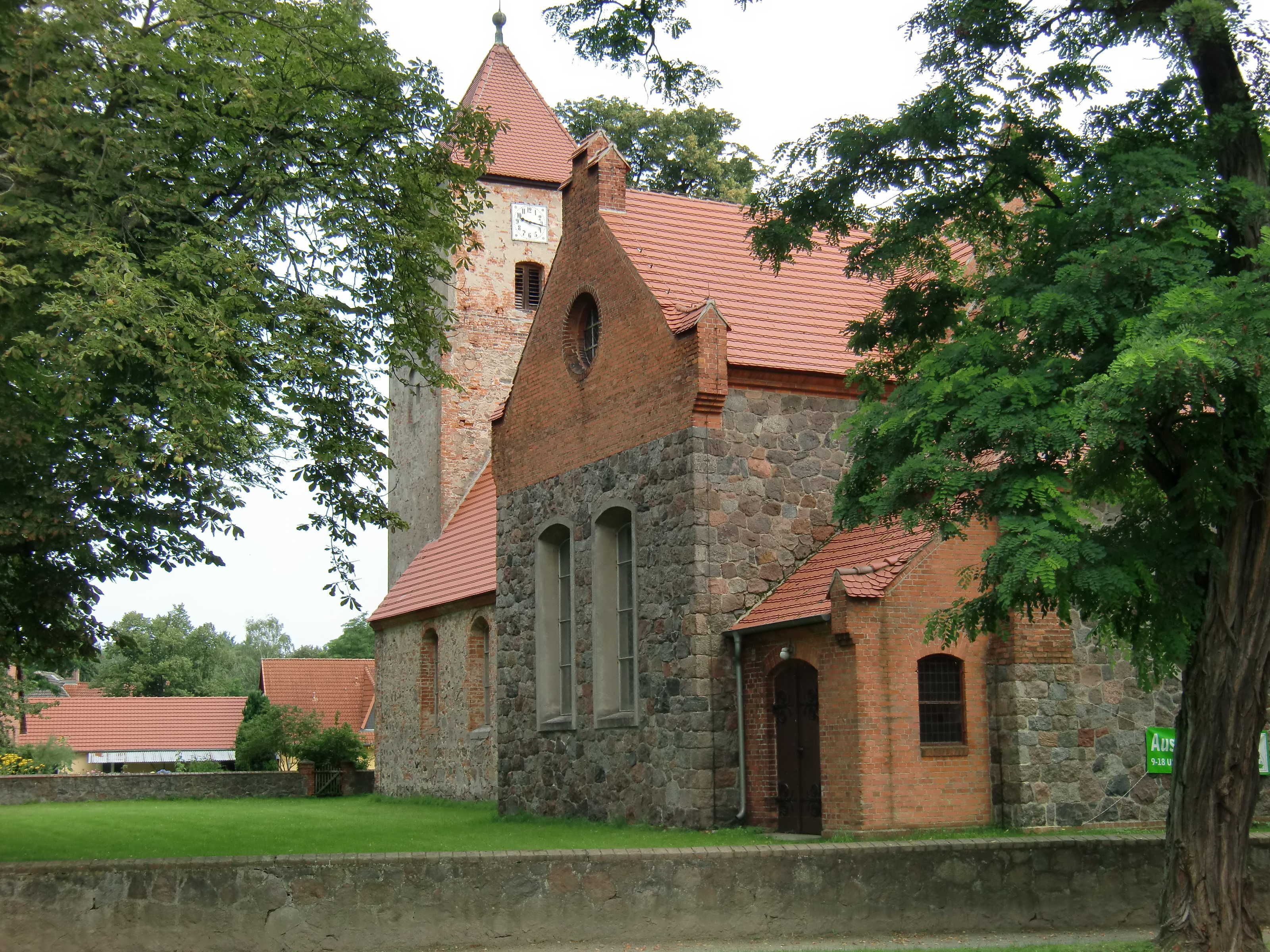 A historic church with a red-tiled roof, stone walls, and a clock tower.