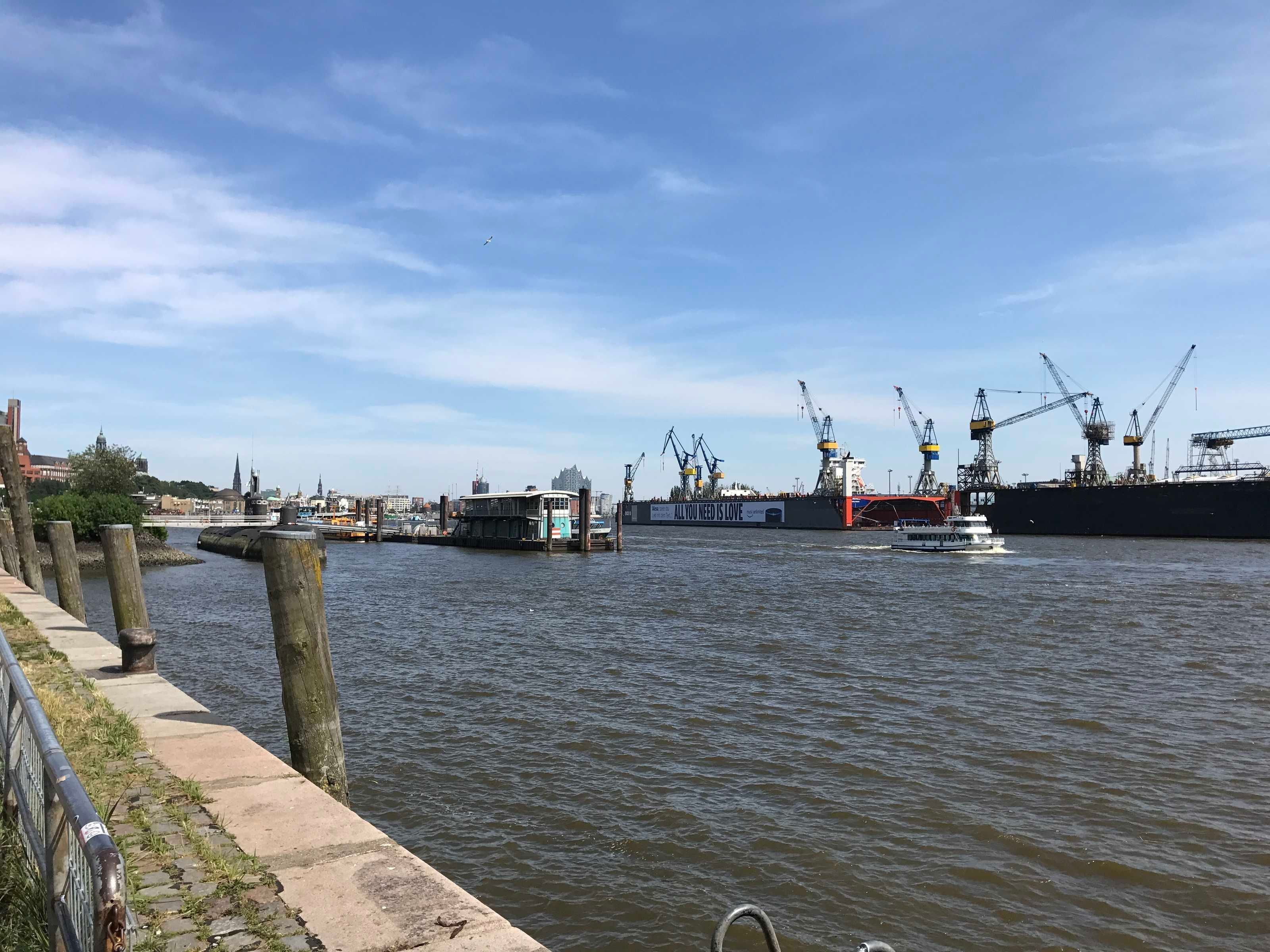 Un port où l’on peut voir un grand navire, de plus petits bateaux et des grues industrielles.
