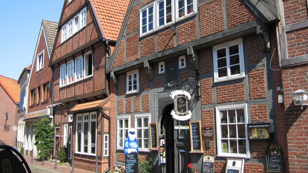 A traditional half-timbered building with multiple windows, a signboard, and a visible entrance.