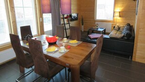 Een houten interieur met een eettafel voor twee personen, een bank en een televisie.