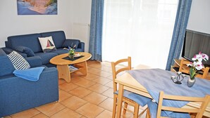 Una sala de estar con un sofá, una mesita y una mesa de comedor con sillas.
