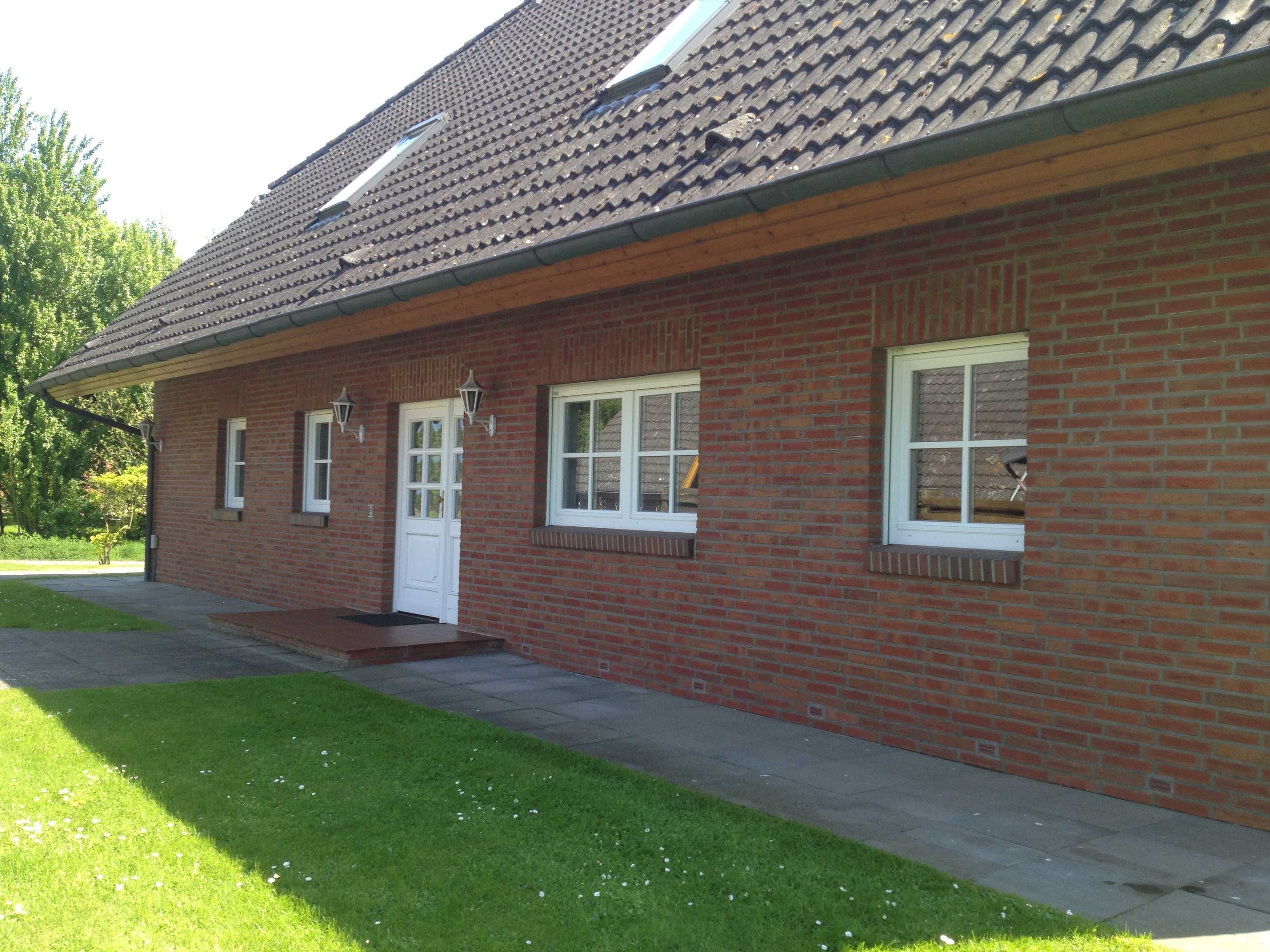 A single-story brick building with a tiled roof, a front door, and three windows.
