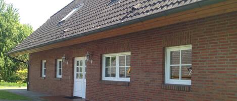 A single-story brick building with a tiled roof, a front door, and three windows.