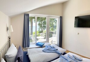 Een hotelkamer met twee bedden, een televisie, een raam met gordijnen en uitzicht op de omgeving.