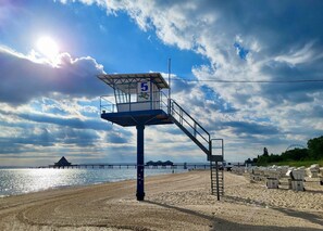Une tour de surveillance avec le numéro 5, surplombant une plage où l’on aperçoit une jetée au loin.