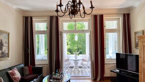 A living room with a sofa, a glass coffee table, a TV, and a chandelier. - a. First floor - Floor - Villa Achterkerke (Heringsdorf)