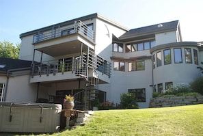 Een modern huis met twee verdiepingen, een balkon en een overdekt terras.