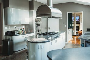A modern kitchen with a central island, stainless steel appliances, and a view into the living area.