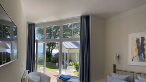 Une chambre avec une grande fenêtre, un lit, une chaise et une vue sur l’extérieur.