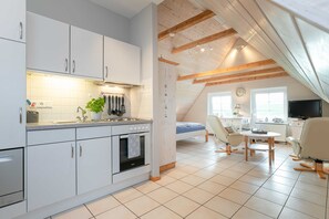 Une cuisine moderne avec des armoires blanches, un four encastré et un coin repas comprenant une table et des chaises.