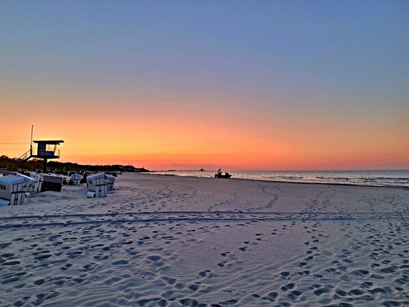A beach with footprints, a lifeguard tower, and beach chairs.