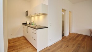 A modern kitchen with white cabinets, a black countertop, and a stainless steel sink. - Castle Apartment WE 29 - Hohendorf Castle (Groß Mohrdorf)