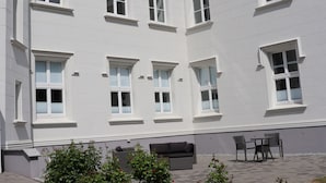 A building with multiple windows and a patio area with outdoor furniture. - Castle Apartment WE 29 - Hohendorf Castle (Groß Mohrdorf)