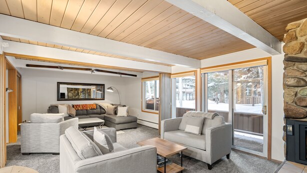 Ein modernes Wohnzimmer mit grauen Sofas, einem Holztisch und einem Kamin aus Stein.