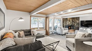 Ein modernes Wohnzimmer mit Kamin aus Stein, einem großen Fernseher und einer gemütlichen Sitzecke.