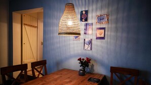 A wooden dining table with chairs, a hanging light fixture, and framed pictures on the wall.