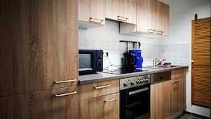 A kitchen with wooden cabinets, a microwave, a coffee maker, and a sink.
